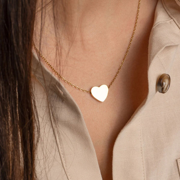 Heart-shaped pendant necklace worn by a person in a beige coat.
