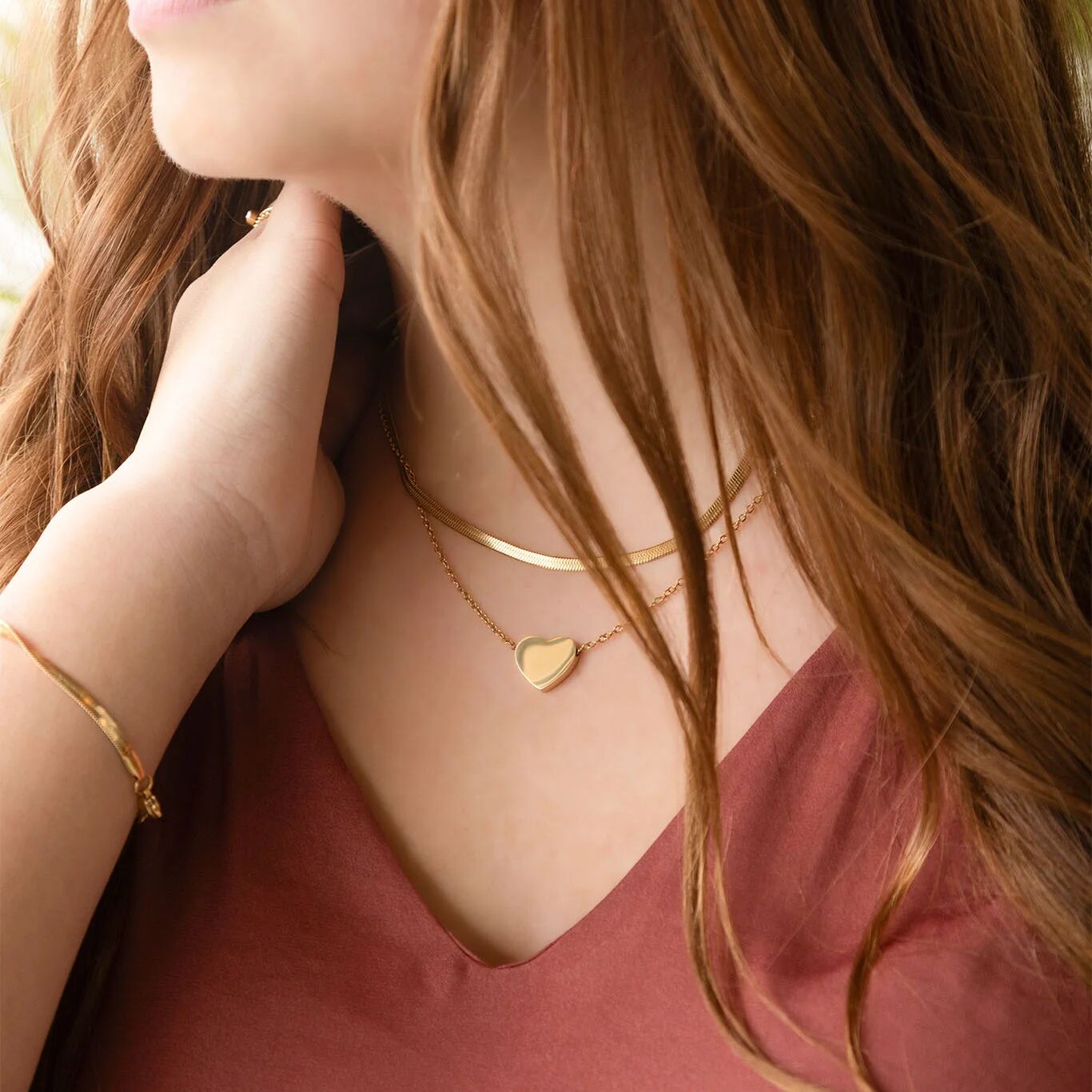 Close-up of a woman wearing gold necklaces and a bracelet with a blurred background