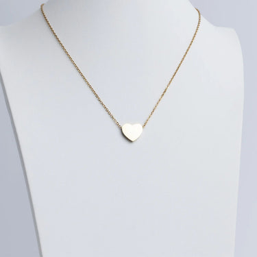 Gold heart-shaped pendant necklace on a mannequin with a plain background
