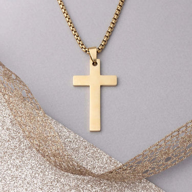 Gold cross necklace on a gray background with gold fabric