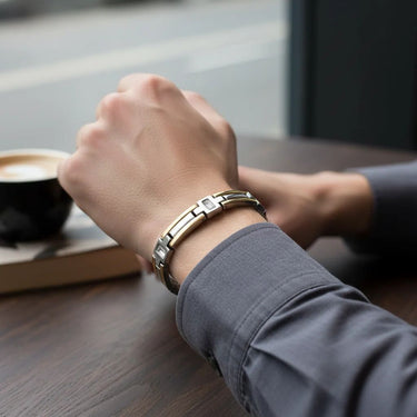 Person wearing a silver bracelet on a wooden table with a blurred background
