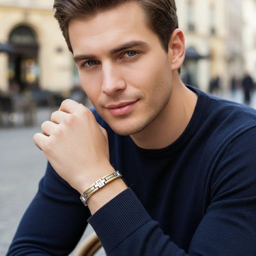 Man wearing a navy sweater and gold bracelet in an urban setting
