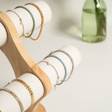 Bracelets on a wooden and white stand with a blurred background.