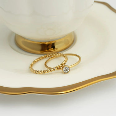 Gold rings with a diamond on a white dish with gold rim