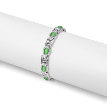 A stainless steel magnetic bracelet with green stone accents displayed on a white cylindrical stand.