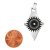 Stainless steel black sun with Greek Key pattern and small Cubic Zirconia on the side pendant with a penny for scale.