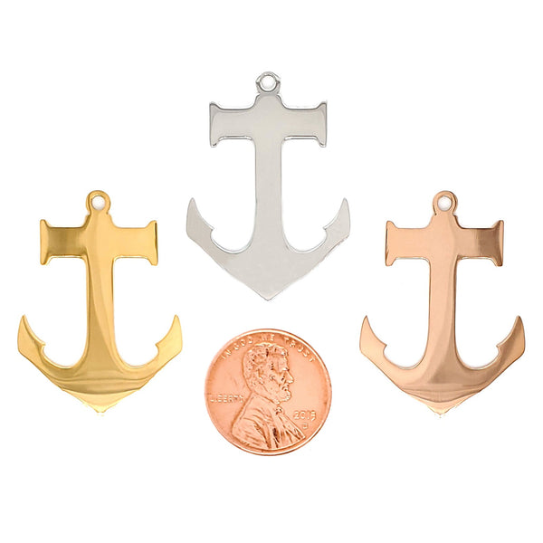 Stainless steel blank anchor pendants in three different colors with a penny for scale.