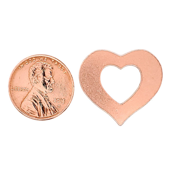 Copper blank heart outline pendant with a penny for scale.