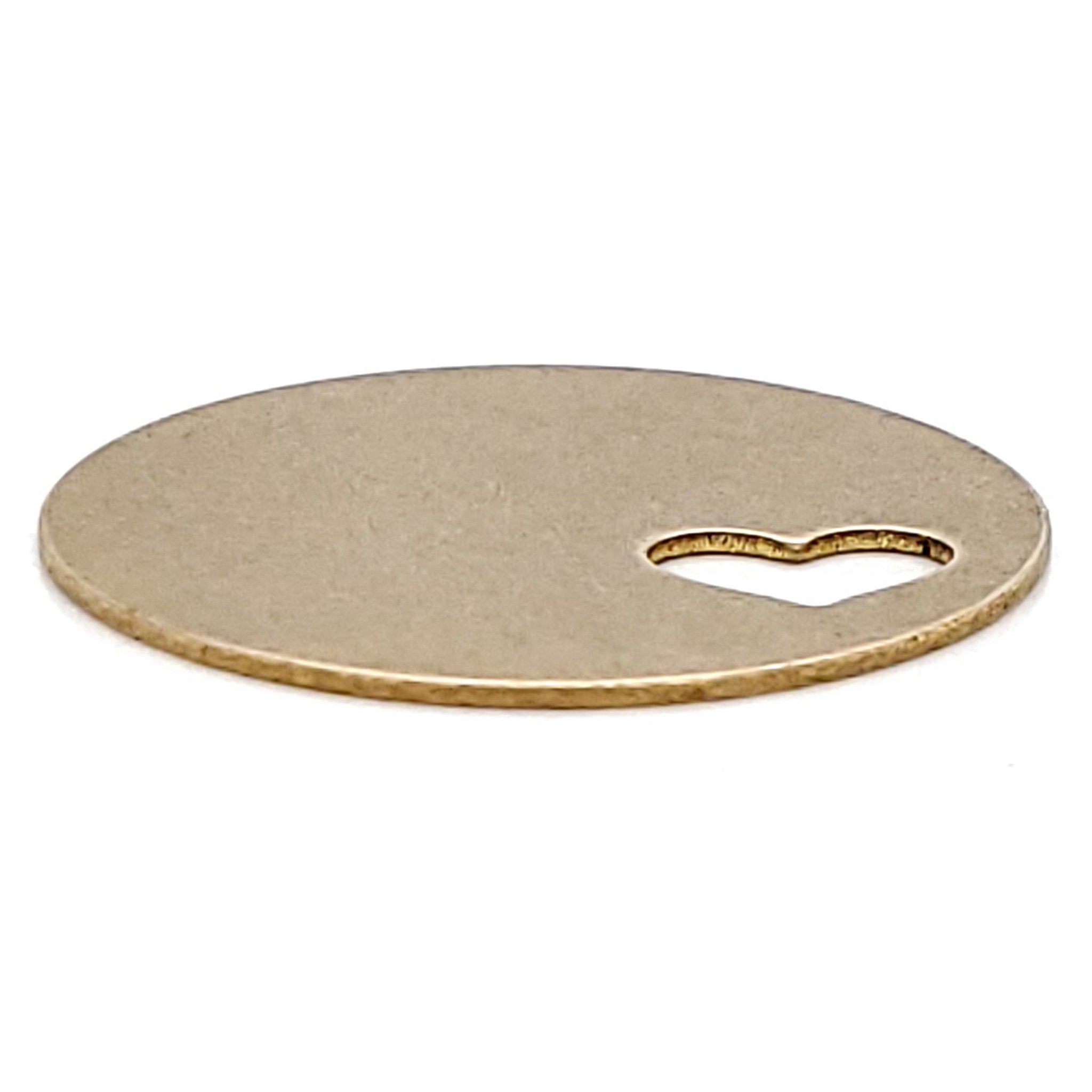 Brass blank round heart cutout pendant at an angle.