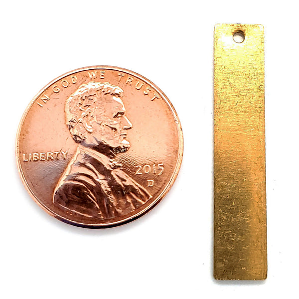 Brass blank vertical rectangle pendant with a penny for scale.