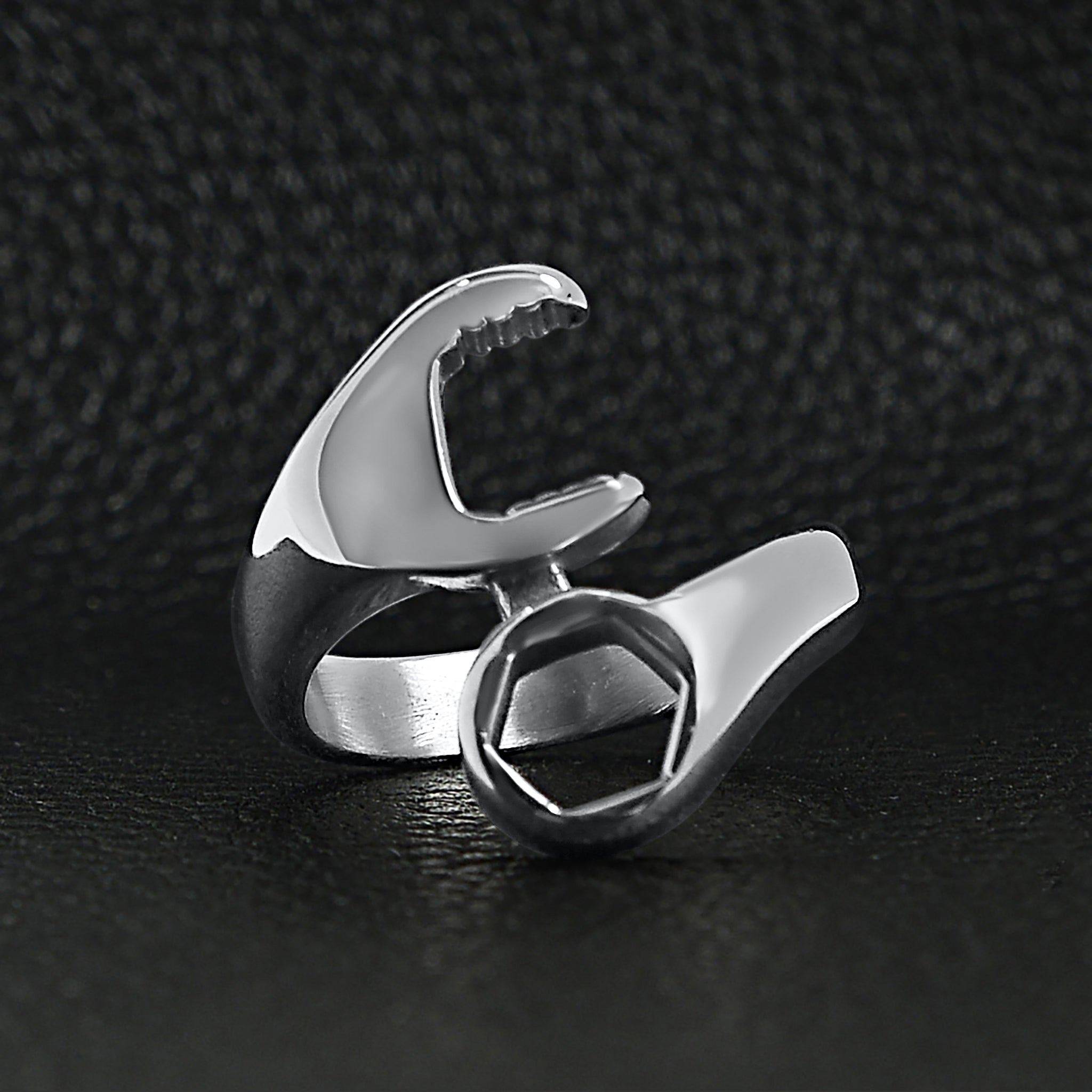 Stainless steel wrench ring on a black leather background.