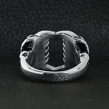 Stainless steel polished heart gripped by bone hands ring back view on a black leather background.
