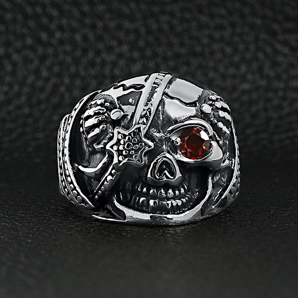 Stainless steel skull with red Cubic Zirconia eye and eyepatch ring on a black leather background.
