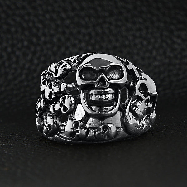Stainless steel polished multiple skulls ring on a black leather background.