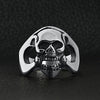 Stainless steel polished skull ring on a black leather background.