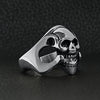 Stainless steel polished skull ring angled on a black leather background.