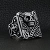 Stainless steel polished studded skull ring angled on a black leather background.
