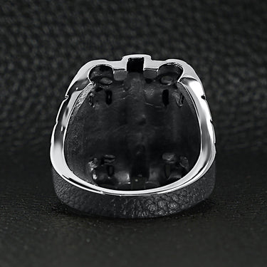 Stainless steel polished multi skull Cross ring back view on a black leather background.