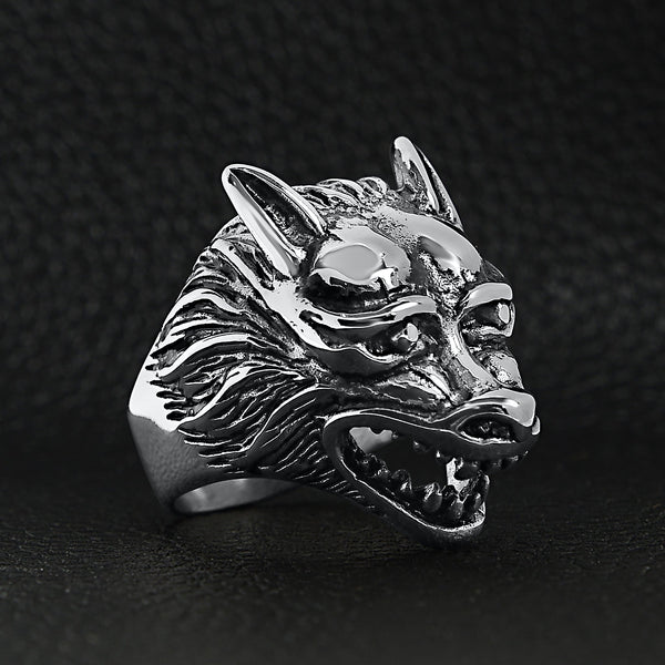 Stainless steel polished snarling wolf ring angled on a black leather background.