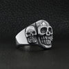 Stainless steel polished cracked triple skulls ring angled on a black leather background.