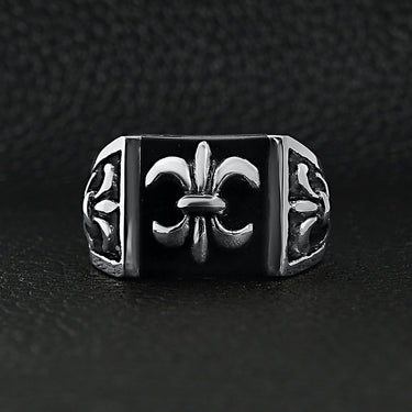 Stainless steel polished black Fleur De Lis ring on a black leather background.