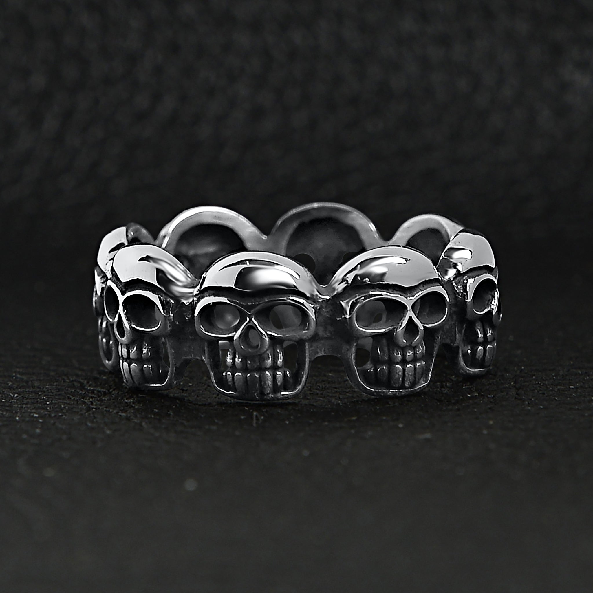 Stainless steel polished multi skull ring on a black leather background.