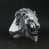 Stainless steel roaring lion head ring angled on a black leather background.