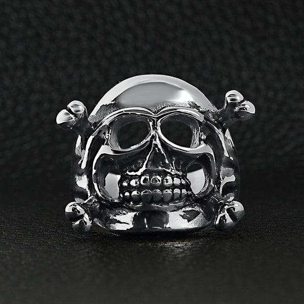 Stainless steel skull and crossbones ring on a black leather background.