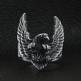 Stainless steel flying eagle ring on a black leather background.