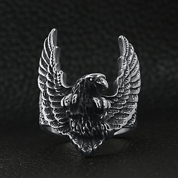 Stainless steel flying eagle ring on a black leather background.