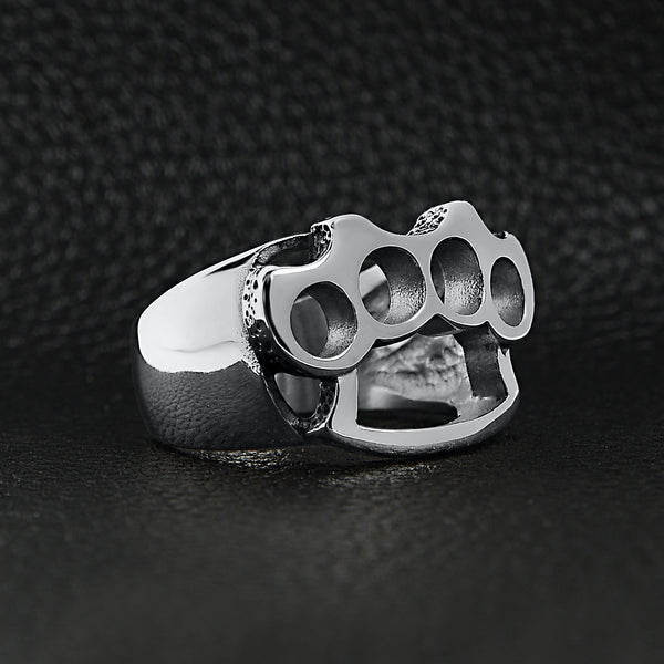 Stainless steel polished knuckle duster ring angled on a black leather background.