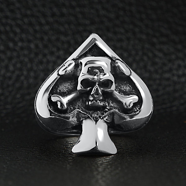 Stainless steel polished skull of spades ace ring on a black leather background.