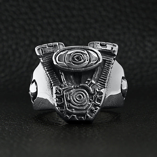Stainless steel motorcycle engine with skull accents ring on a black leather background.