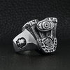 Stainless steel motorcycle engine with skull accents ring angled on a black leather background.