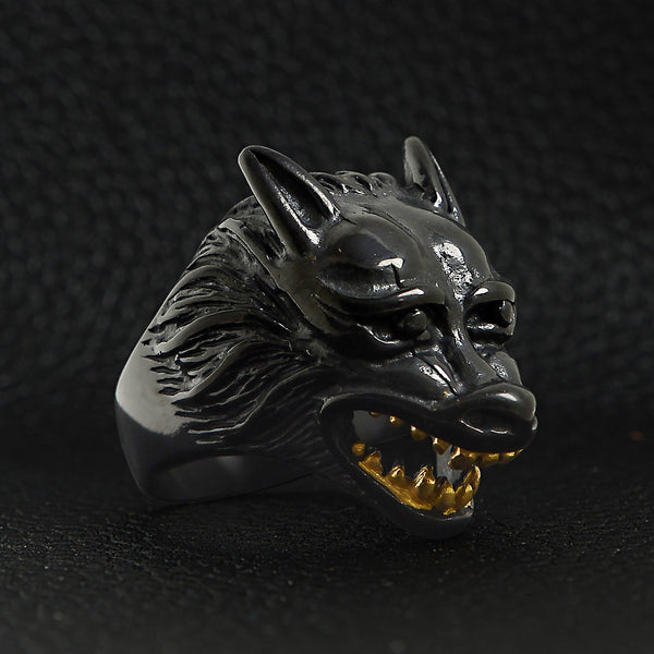 Stainless steel black wolf with 18K gold PVD Coated teeth ring angled on a black leather background.