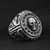 Stainless steel large filigree skull signet ring angled on a black leather background.