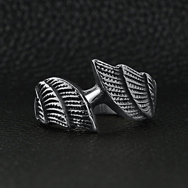 Stainless steel angel wings ring on a black leather background.