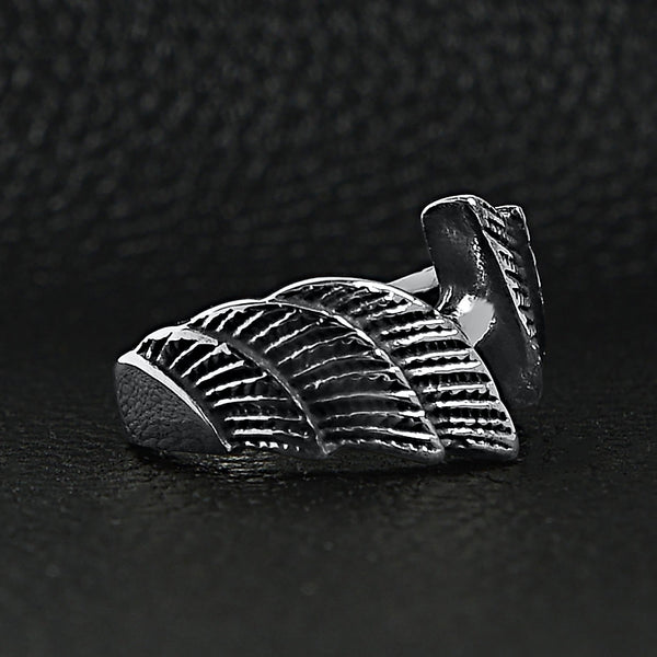 Stainless steel angel wings ring angled on a black leather background.