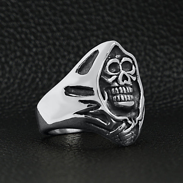 Stainless steel grim reaper skull ring angled on a black leather background.