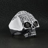 Stainless steel black Cubic Zirconia eyed skull with clear Cubic Zirconia UK flag ring angled on a black leather background.
