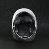 Stainless steel grinning skull ring back view on a black leather background.