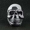 Stainless steel grinning skull ring on a black leather background.