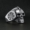 Stainless steel skull with spider and web accents ring angled on a black leather background.