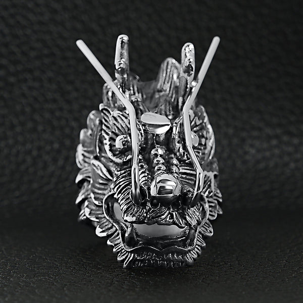 Stainless steel eastern luck dragon head ring on a black leather background.