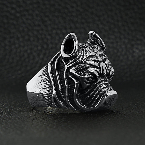 Stainless steel pit bull dog ring angled on a black leather background.