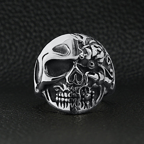 Stainless steel two-faced skull ring on a black leather background.