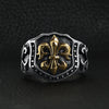 Stainless steel 18K gold PVD Coated Fleur De Lis shield ring on a black leather background.