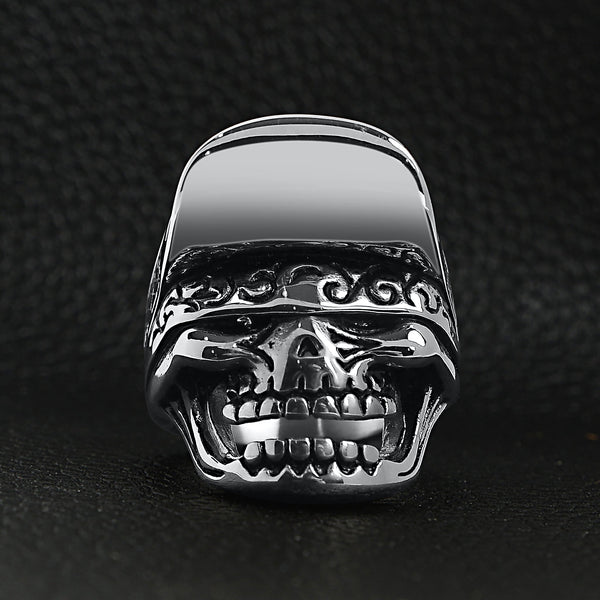 Stainless steel trucker hat skull ring on a black leather background.