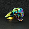 Stainless steel rainbow skull ring angled on a black leather background.