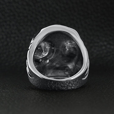 Stainless steel skull smoking 18K gold PVD Coated cigar and single Cubic Zirconia eye ring back view on a black leather background.